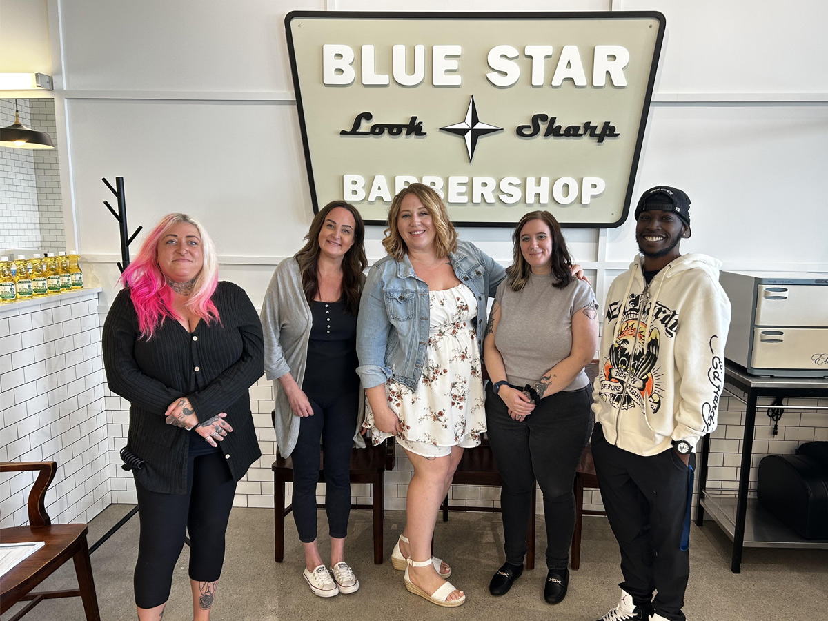 Five Blue Star team members standing together beneath the Blue Star sign