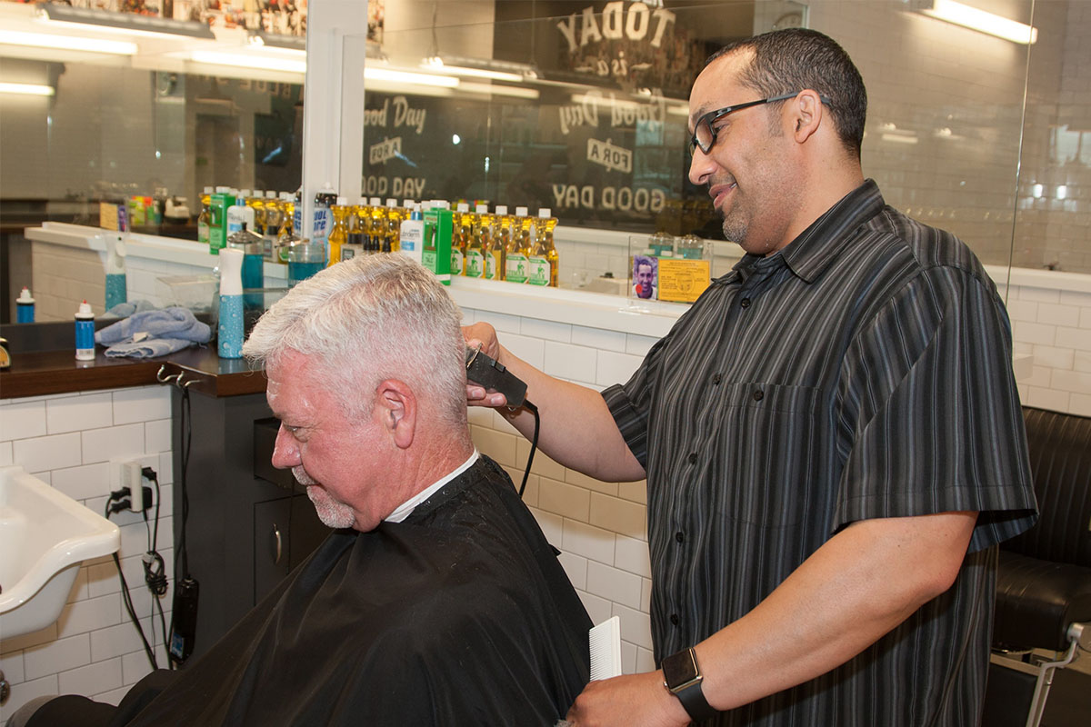Barber trimming the back of a client’s gray hair