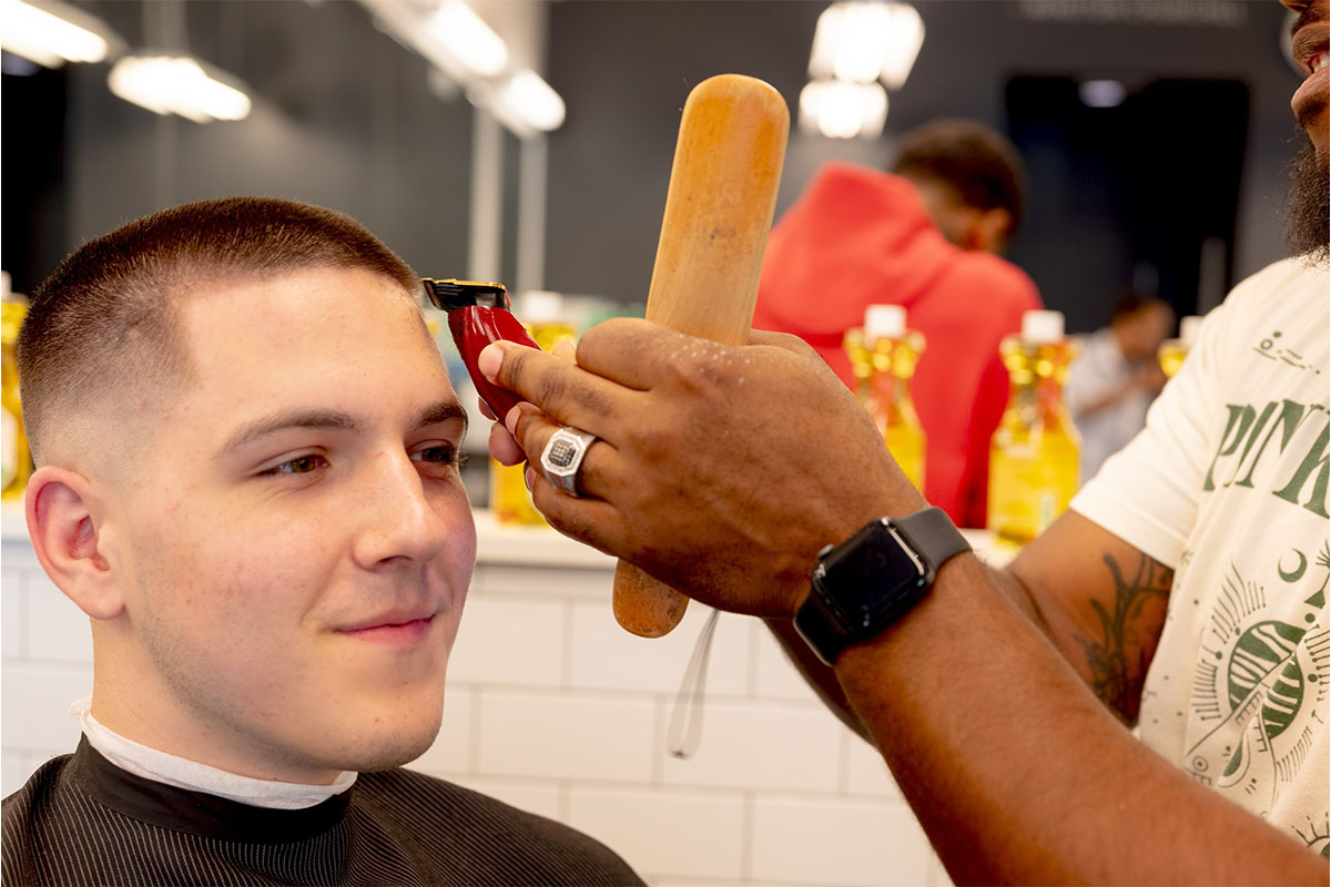 Barber detailing a client’s hairline with trimmers
